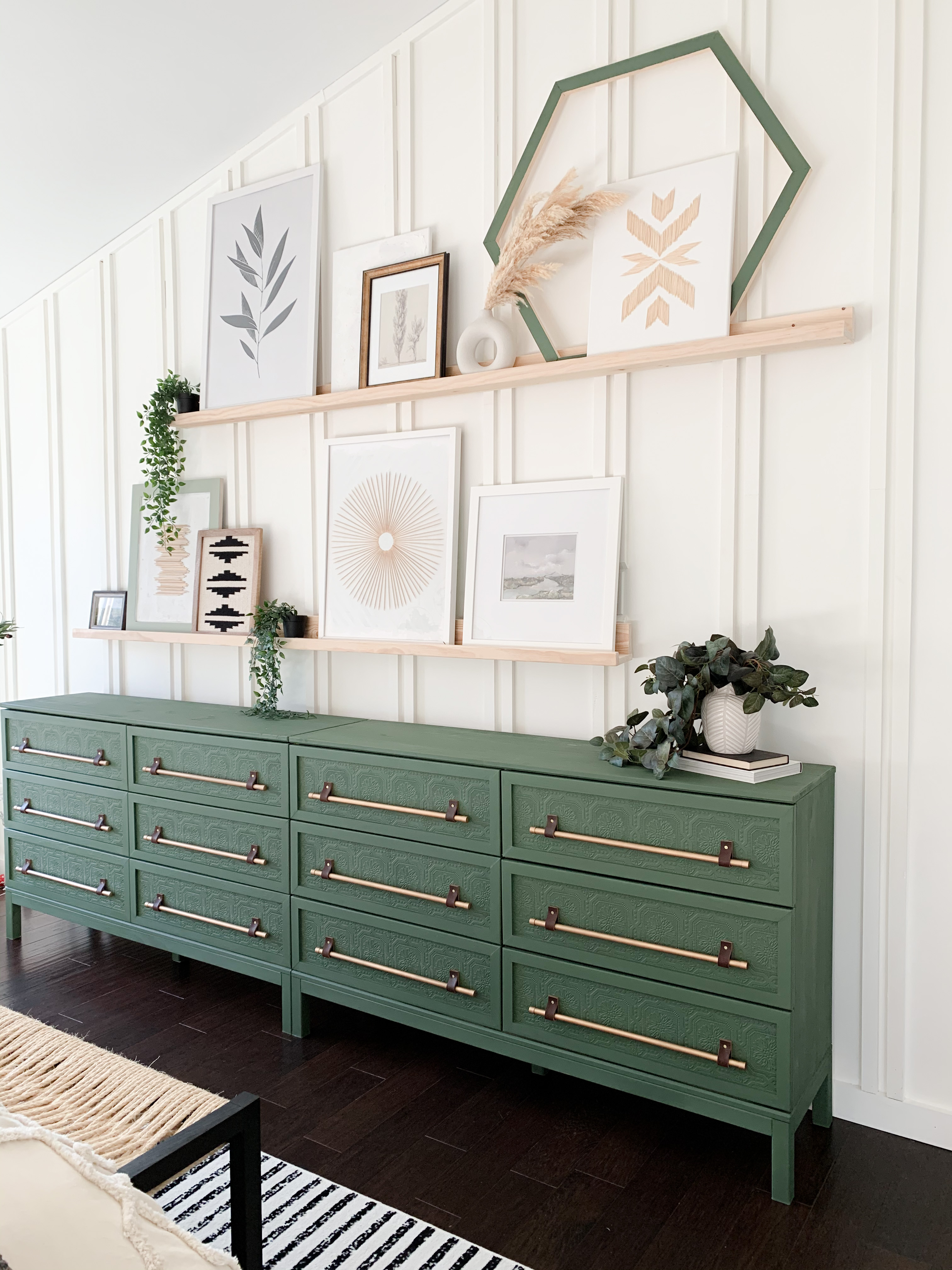 IKEA Tarva Hack with paintable wallpaper and copper pipes in front of a white wall with modern boho art displayed on wooden picture shelves.