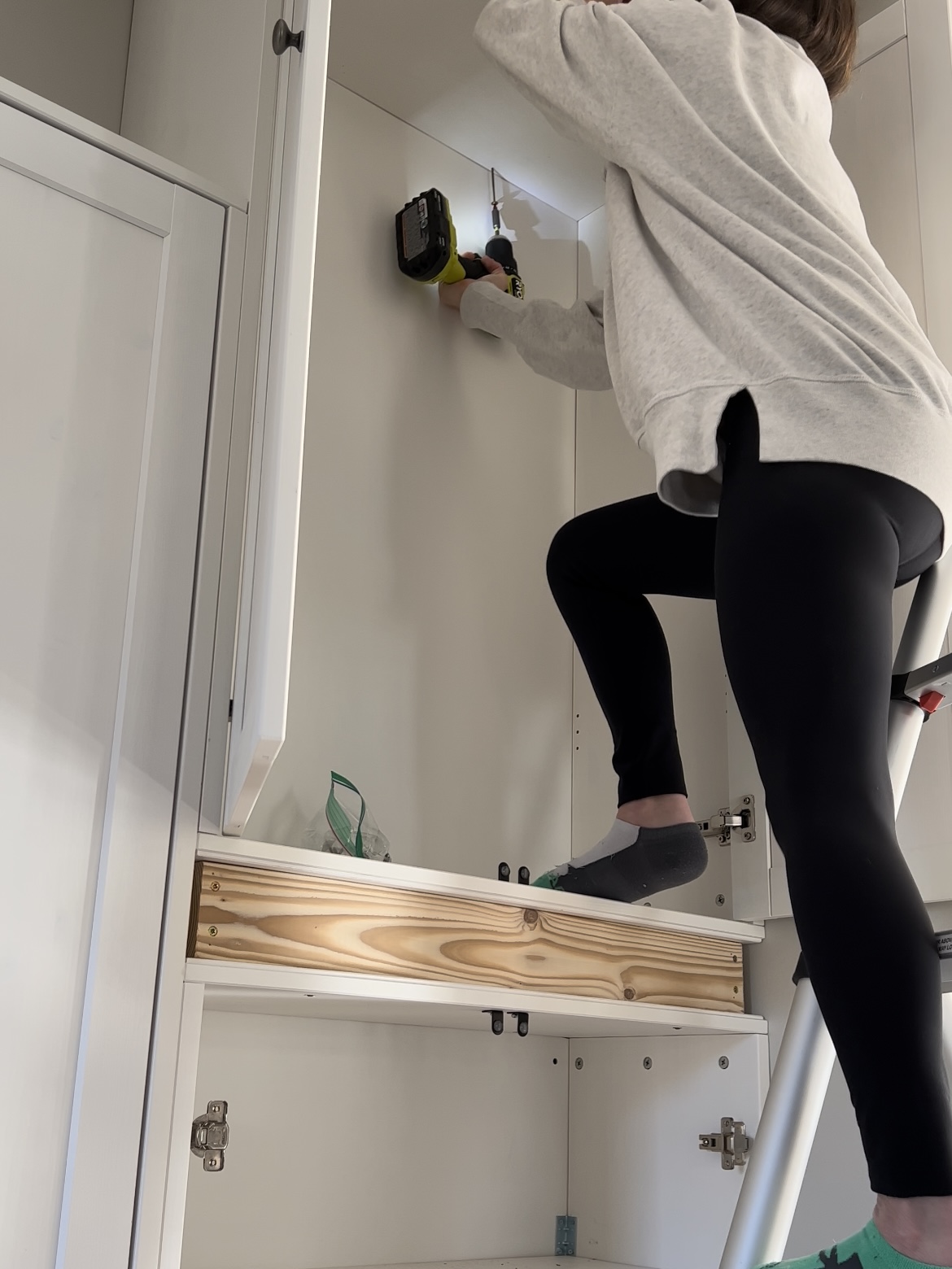 Woman drilling cabinets into top boxes.