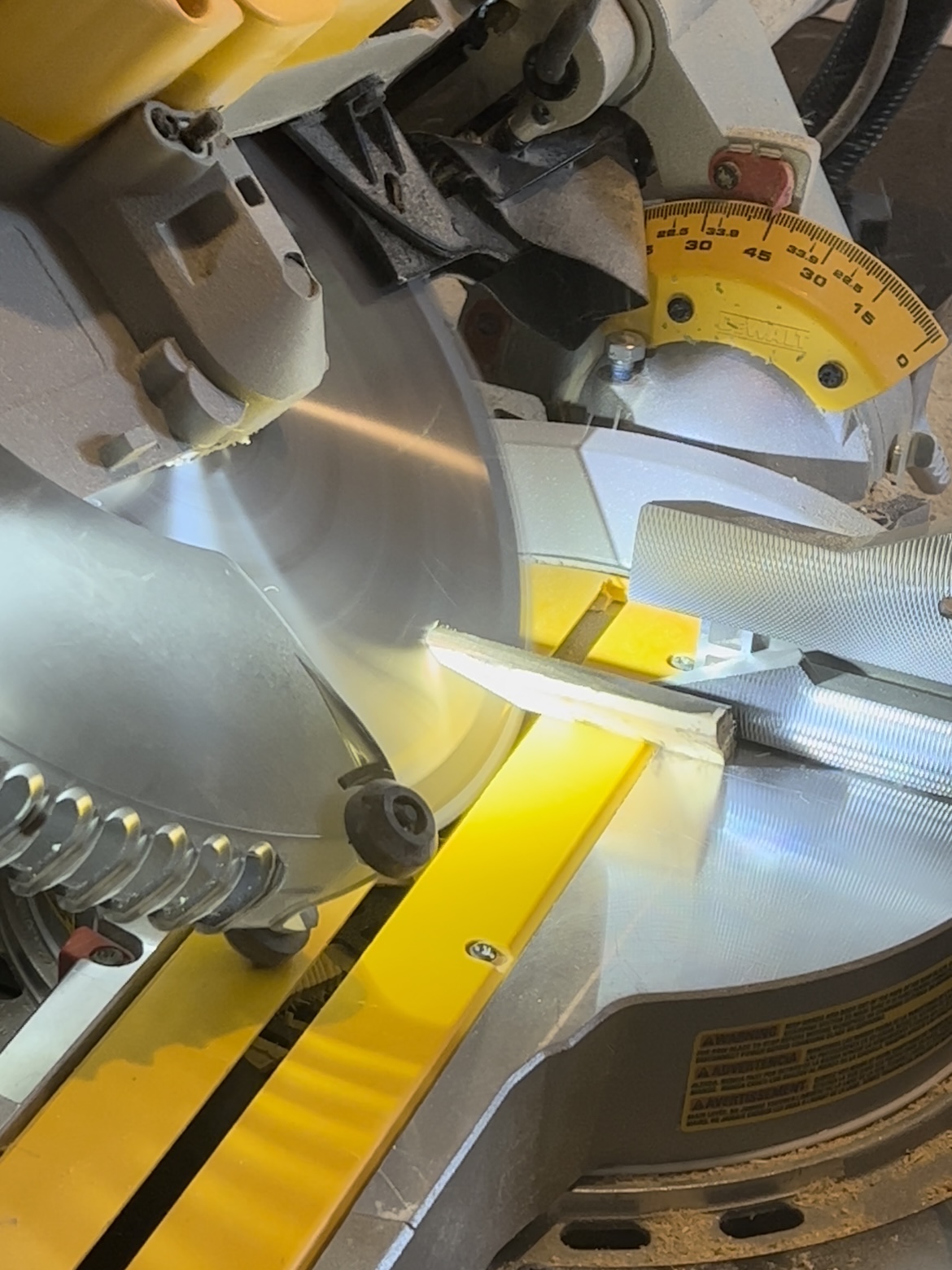 Miter saw cutting trim at a beveled 45 degree angle.
