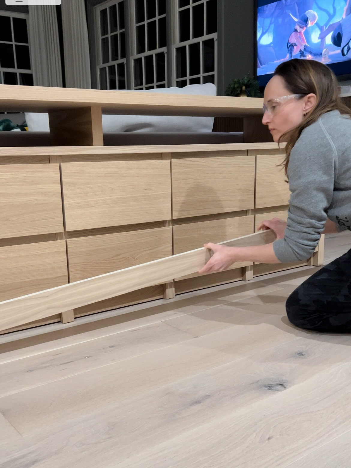 Woman attaching a piece of white oak plywood to the base of the sofa table.