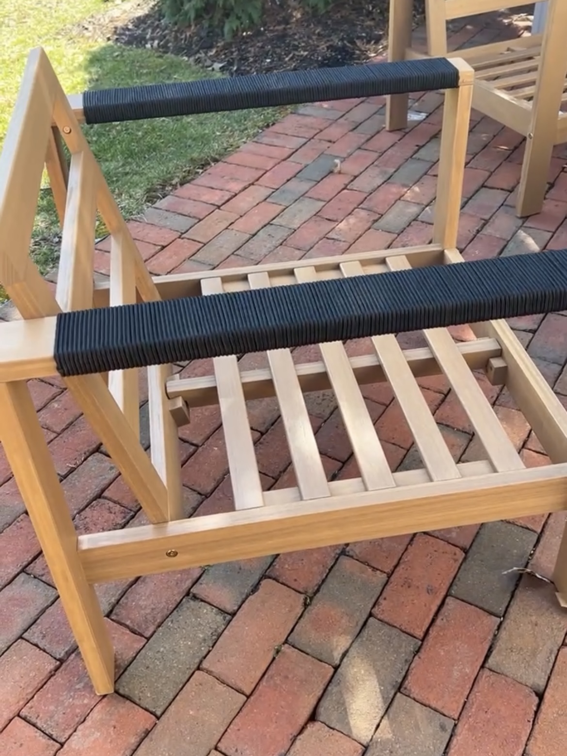 Wooden outdoor chair with black cording on arms.