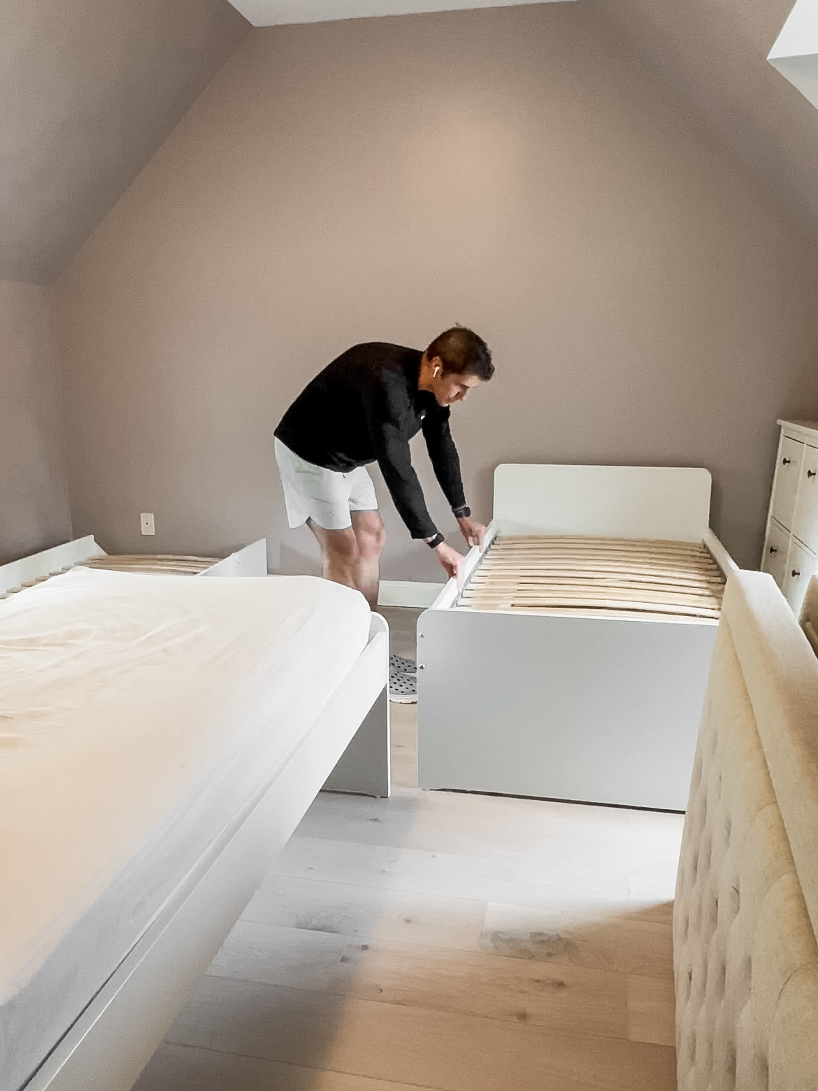 Man putting a trundle bed against a wall.