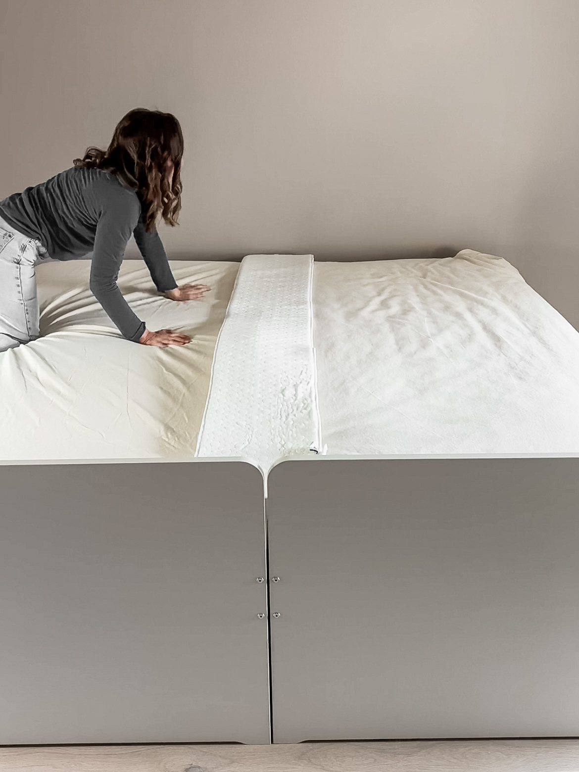Woman placing a bed bridge onto two twin beds pushed together.