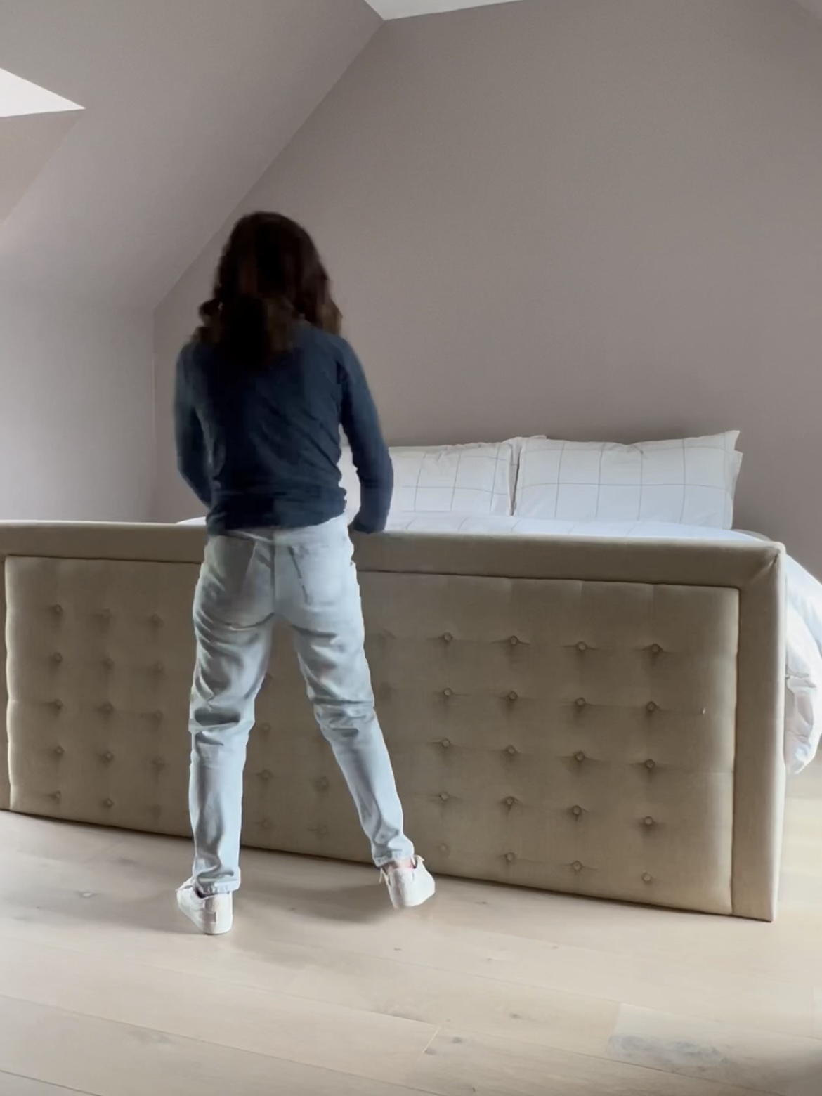 Woman holding a headboard at the foot of a bed.