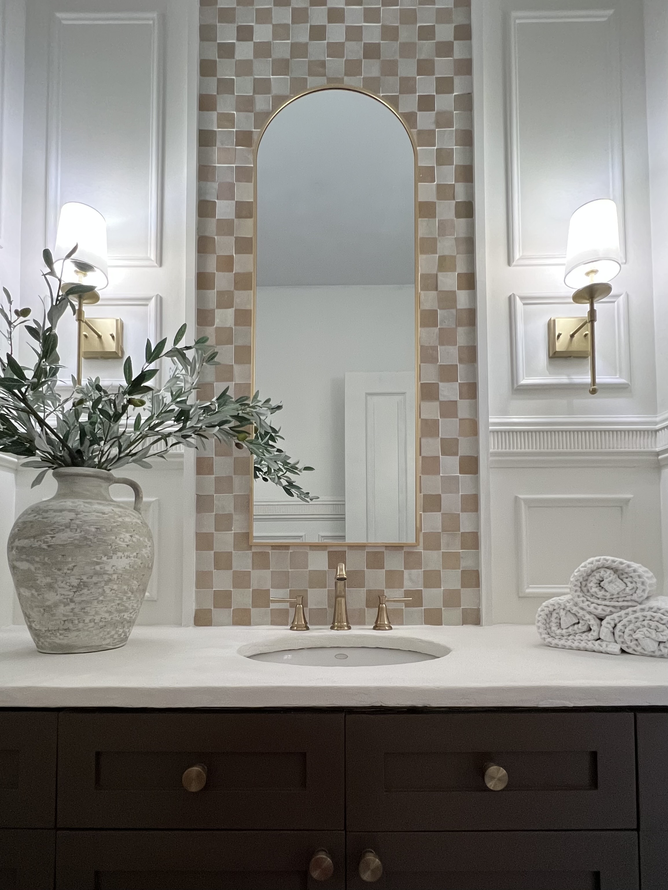 Reveal photo of powder room makeover, with a painted vanity, faux cement countertop, decorative wall trimwork, and Zellige checkerboard tile.