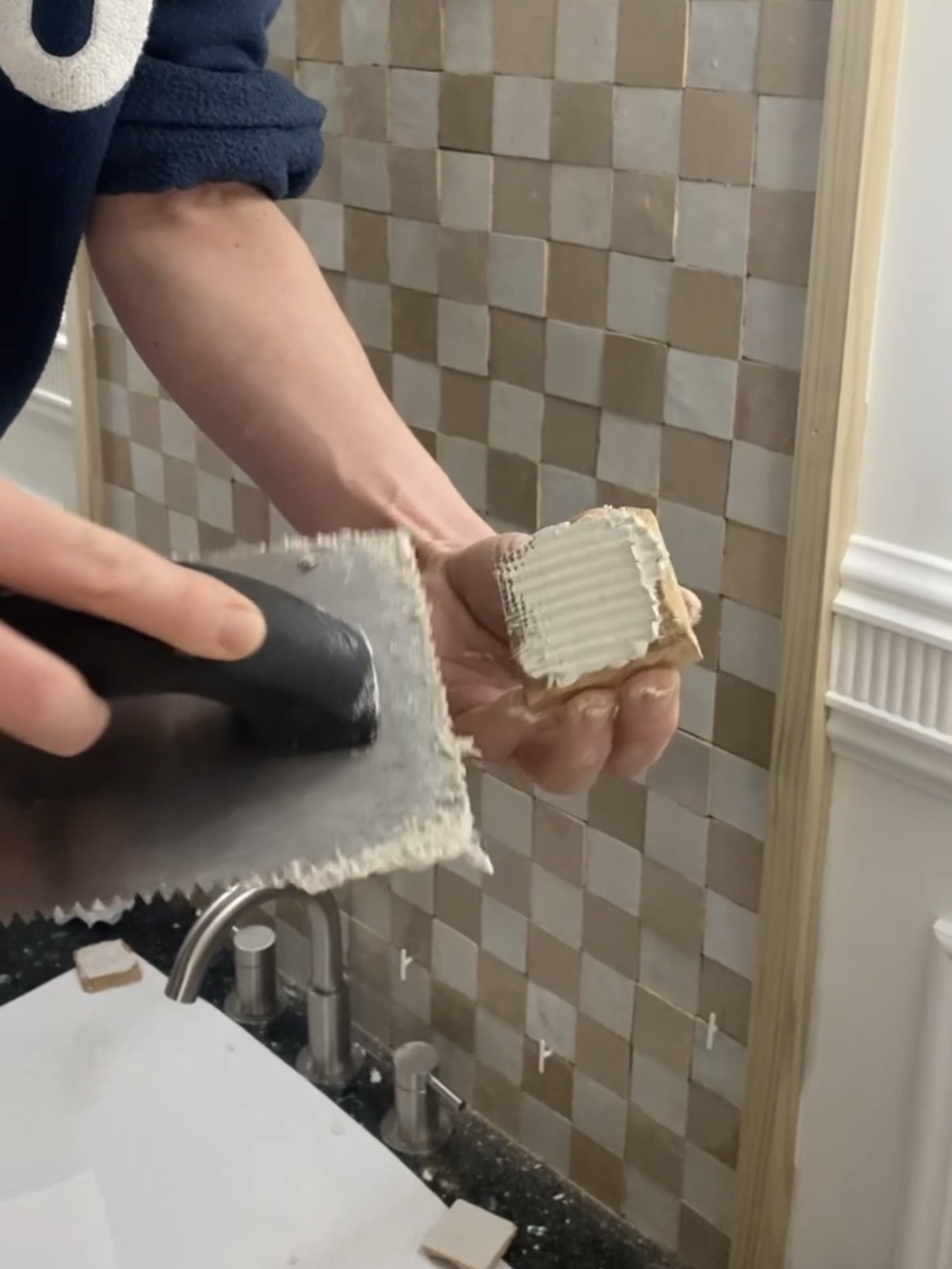 Backbuttering a small zellige tile with thinset using a trowel.