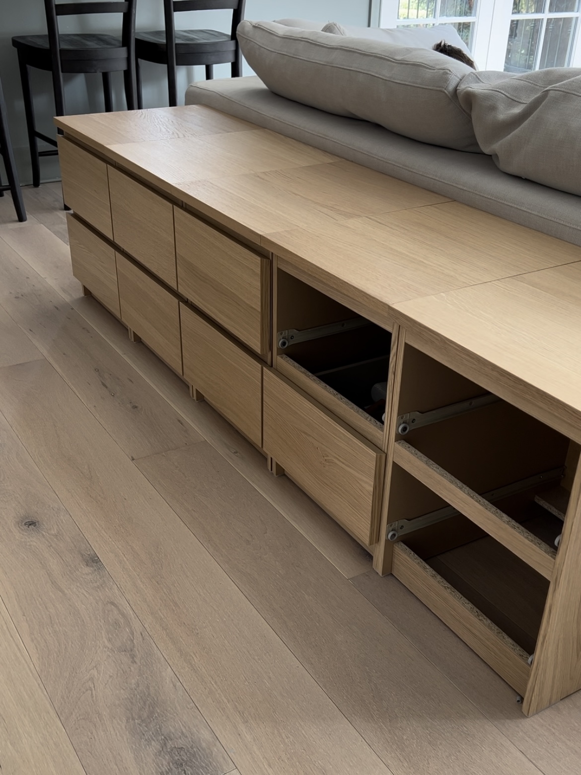 Five Malm nightstands in white oak lined up behind a sofa.