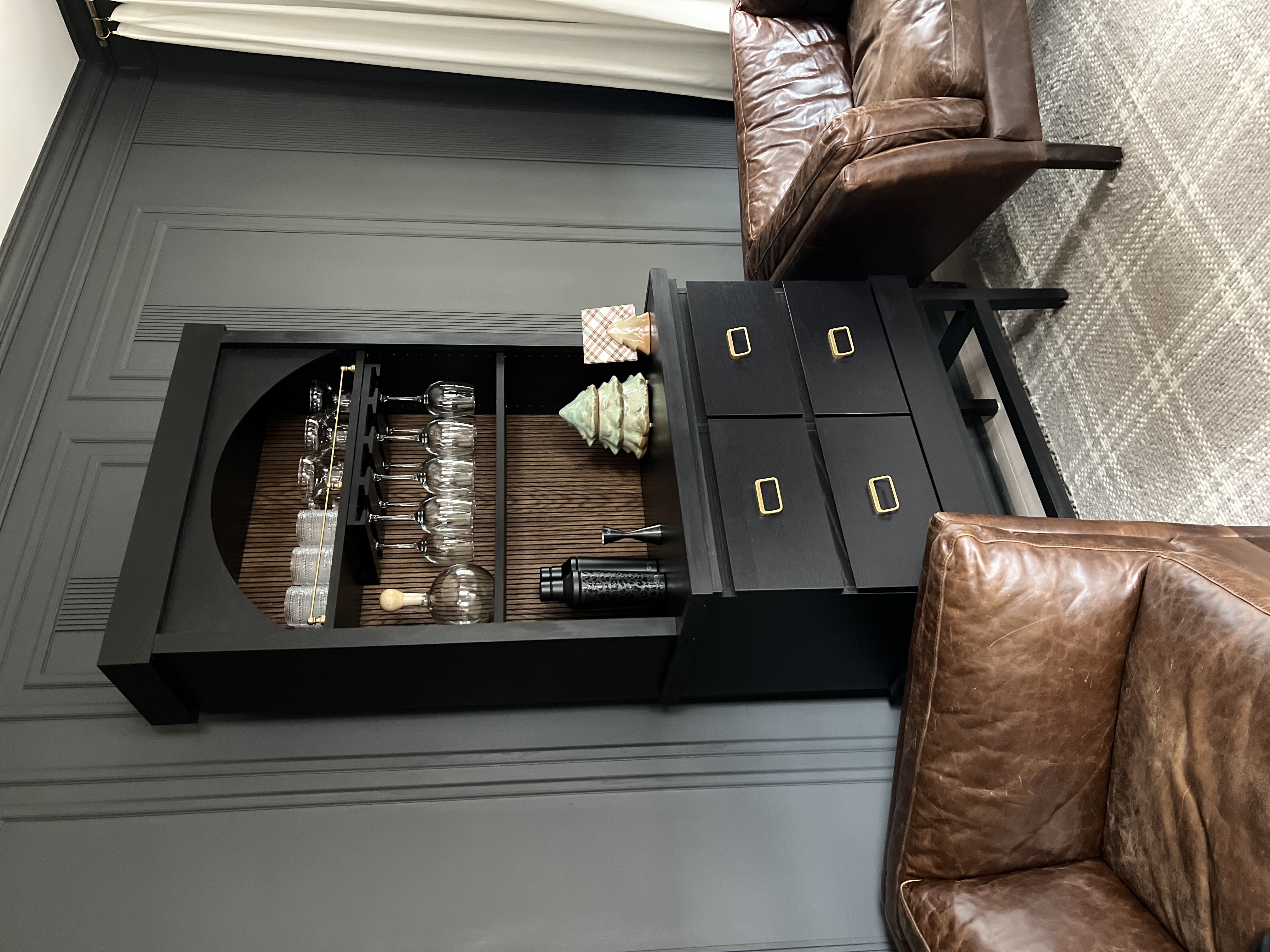 Home bar cabinet in a moody room, flanked by two leather chairs.