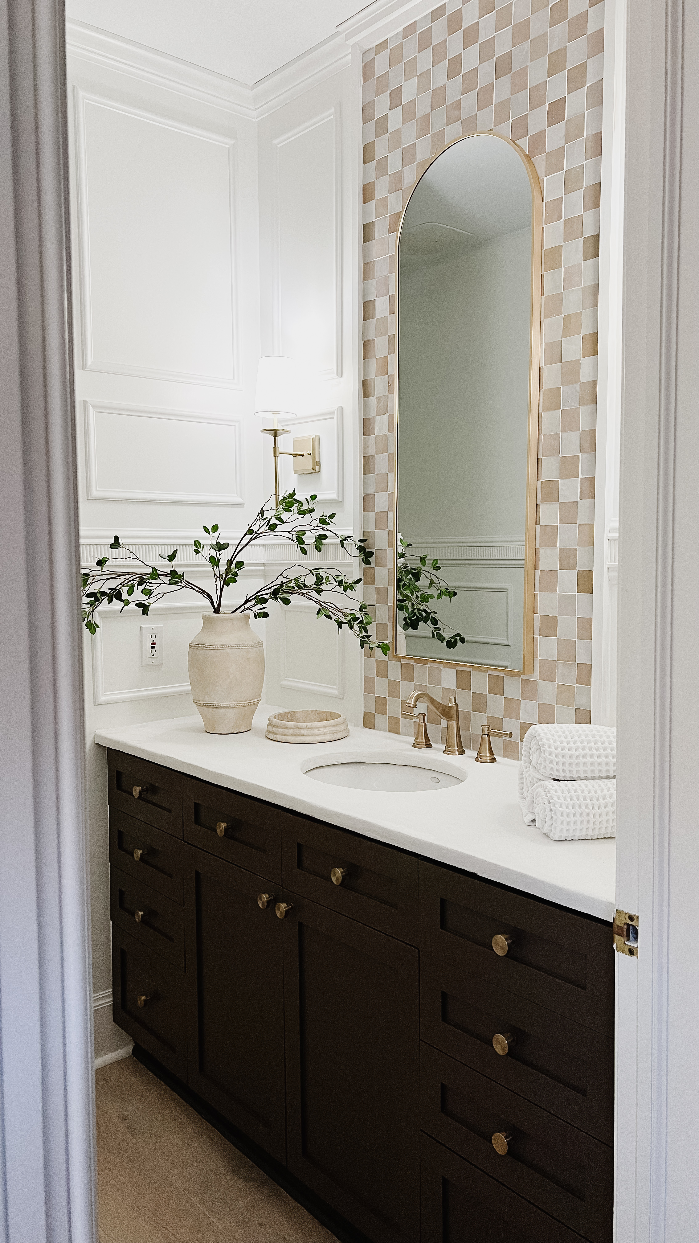 Reveal photo of powder room makeover, with a painted vanity, faux cement countertop, decorative wall trimwork, and Zellige checkerboard tile.