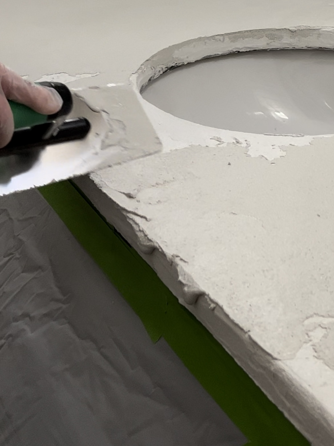 Troweling cement onto bathroom countertop around the sink.