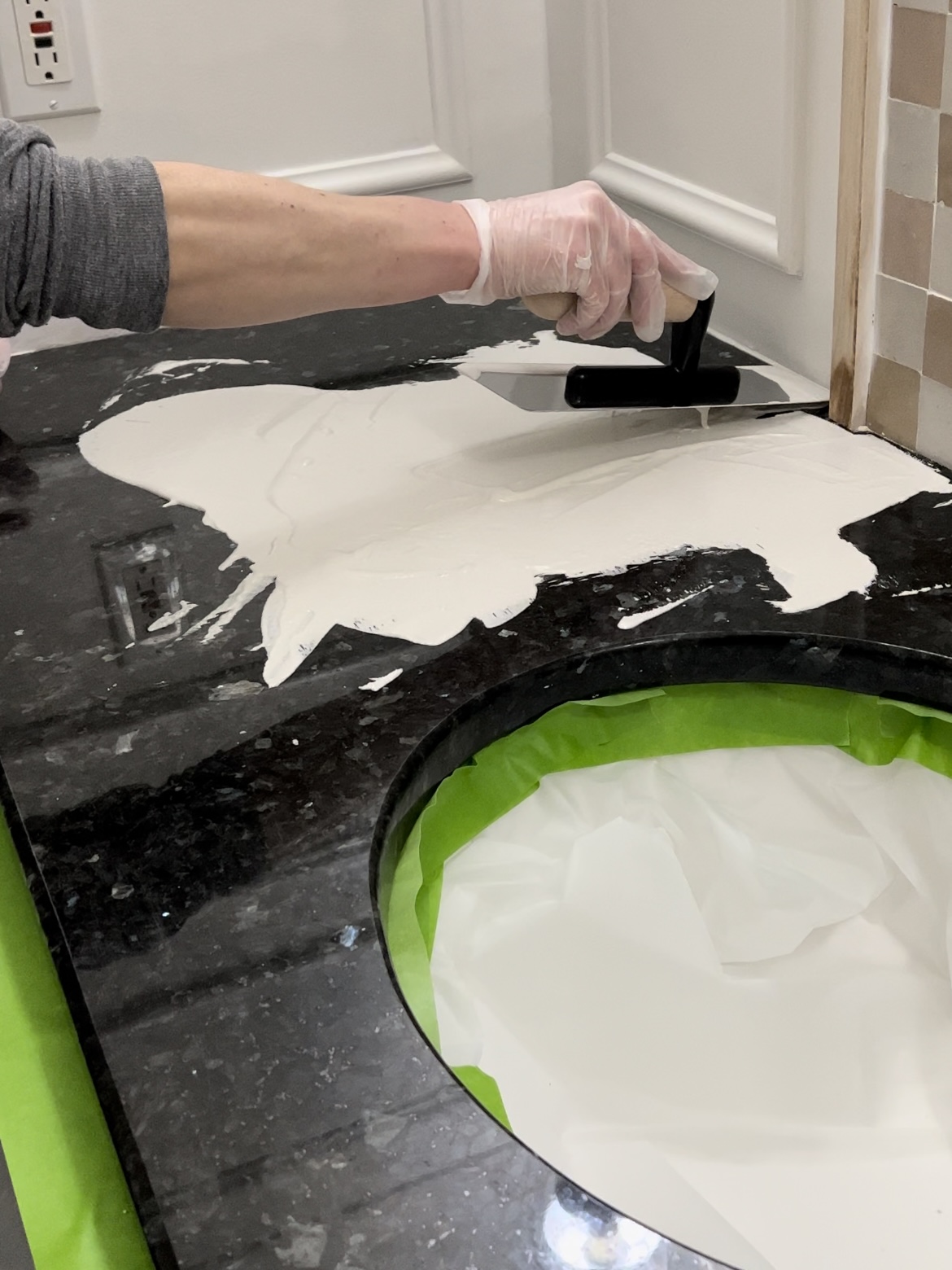 Troweling very wet faux cement onto a black countertop.