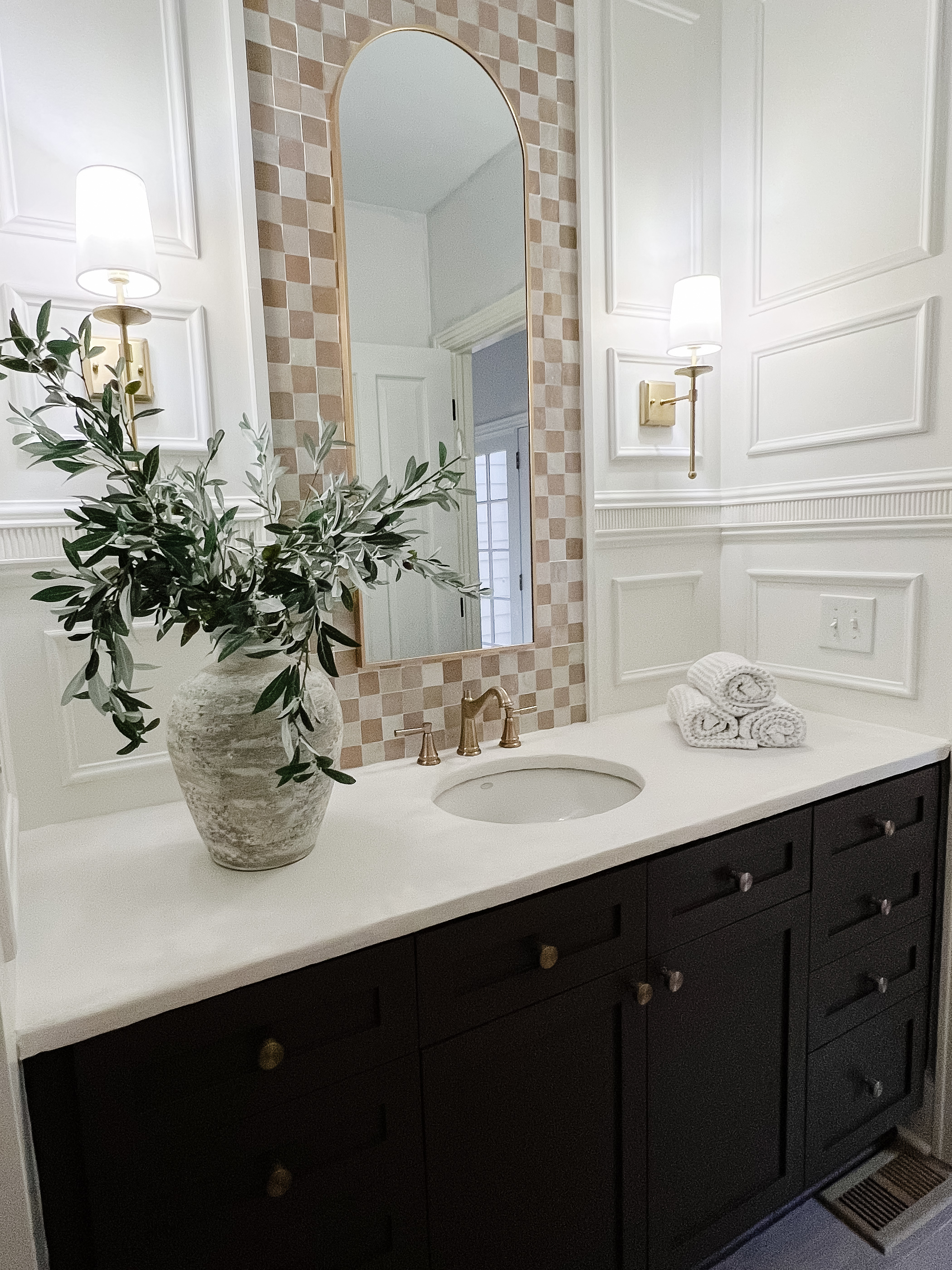 Reveal photo of powder room makeover, with a painted vanity, faux cement countertop, decorative wall trimwork, and Zellige checkerboard tile.