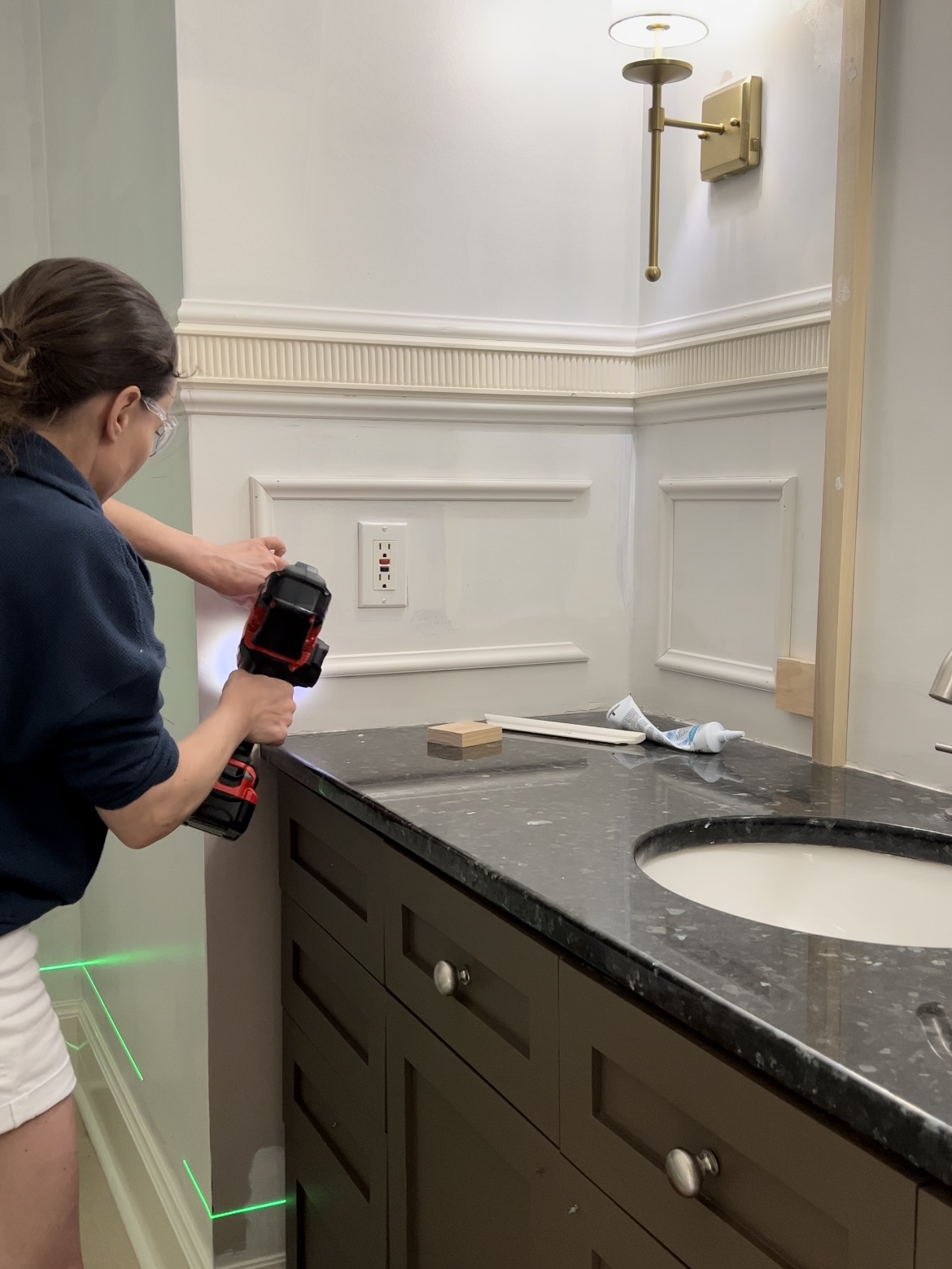 Woman attaching trim to a wall for a powder room makeover.