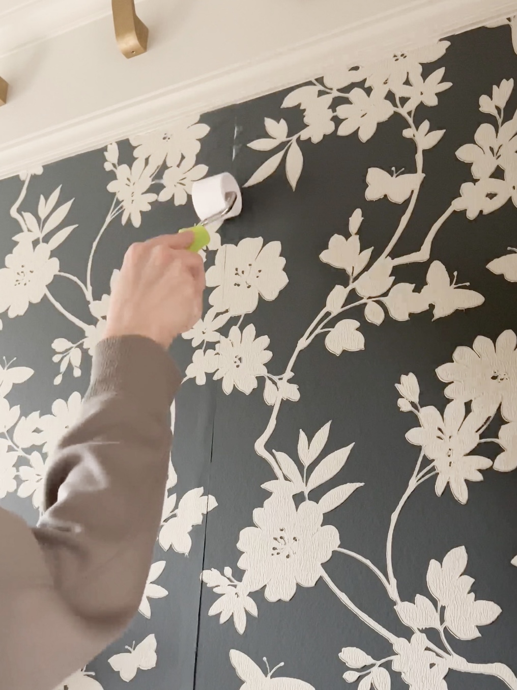 Person rolling wallpaper seams flat.