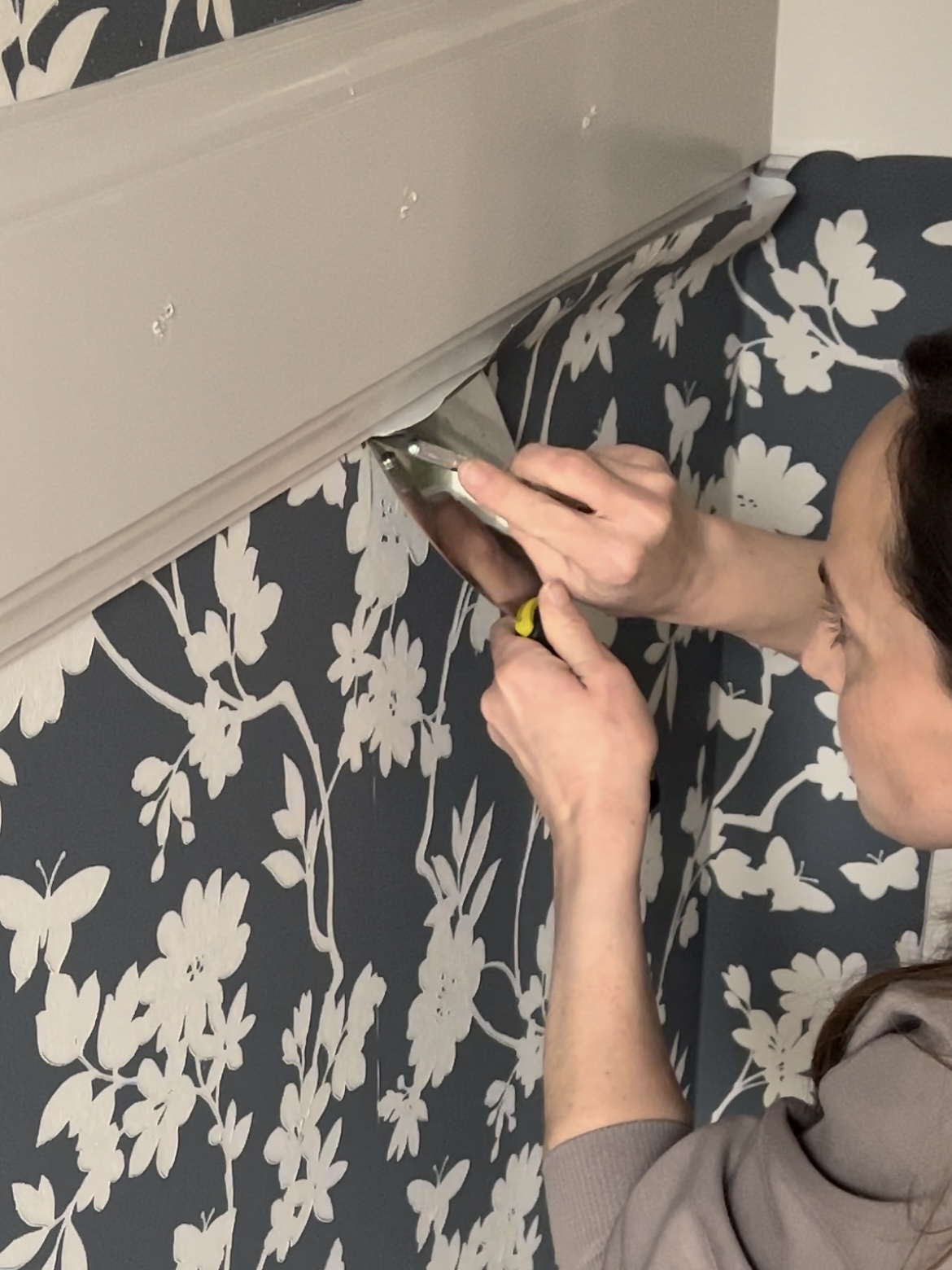 Trimming wallpaper with sharp razor blade.