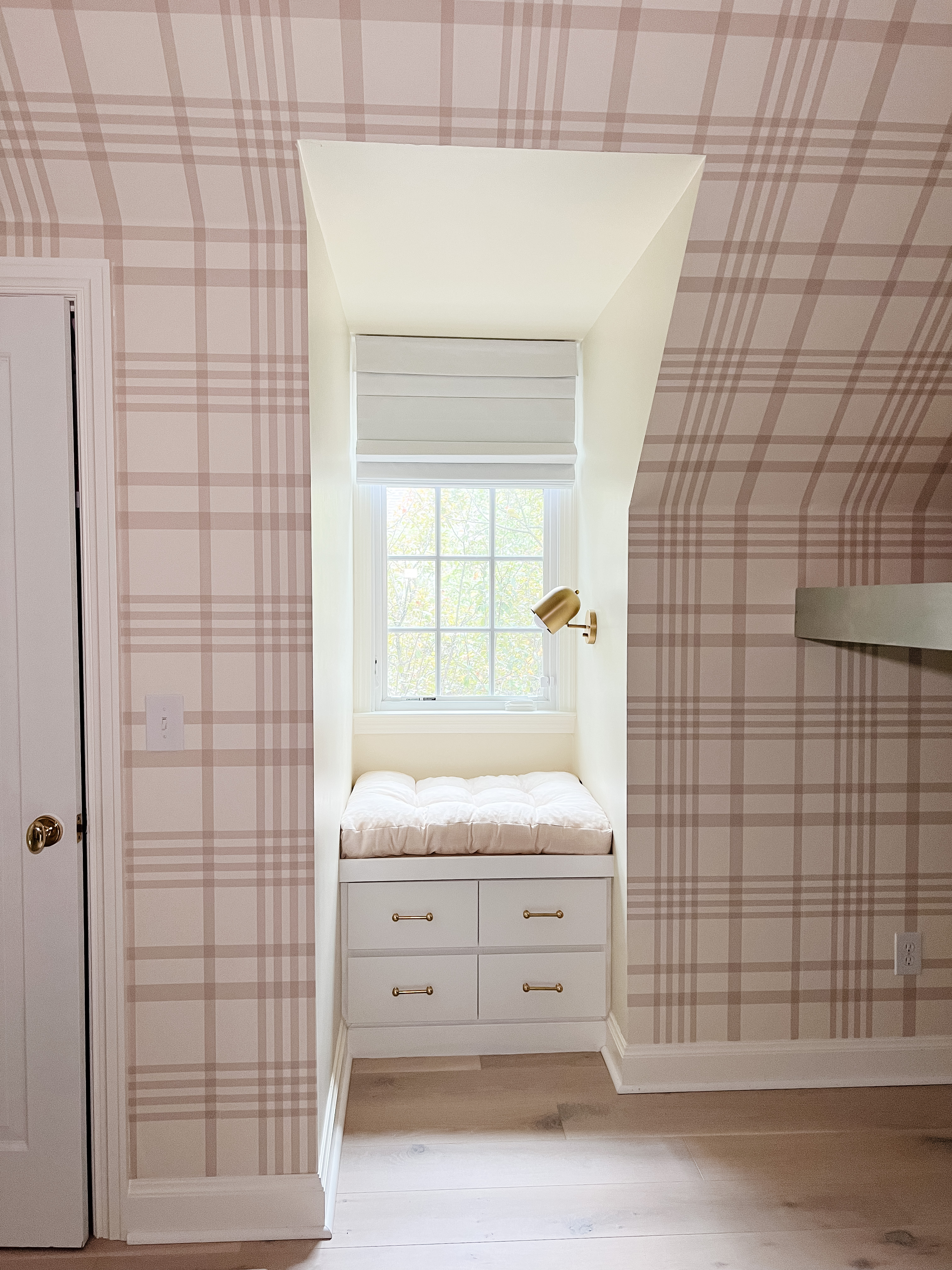 Plaid wallpaper on walls in bedroom with a windowseat.