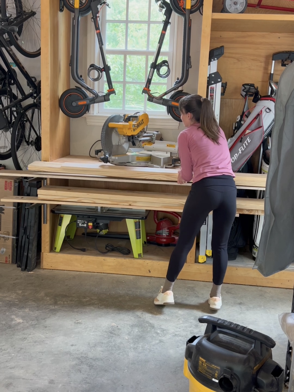 Annie stacking leftover lumber on lumber racks attached to storage cabinets.