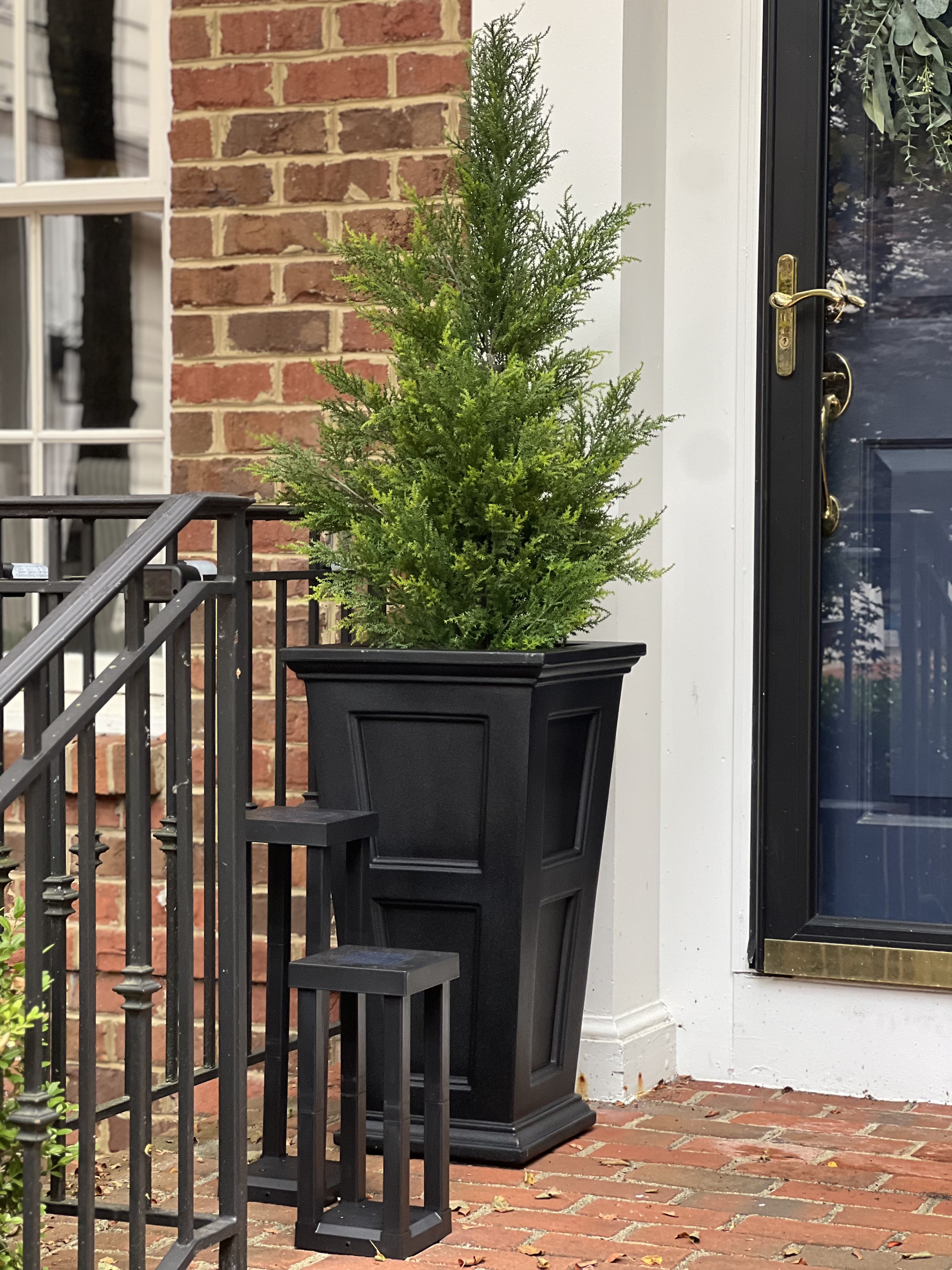 Image of a front porch with artificial evergreens trees.