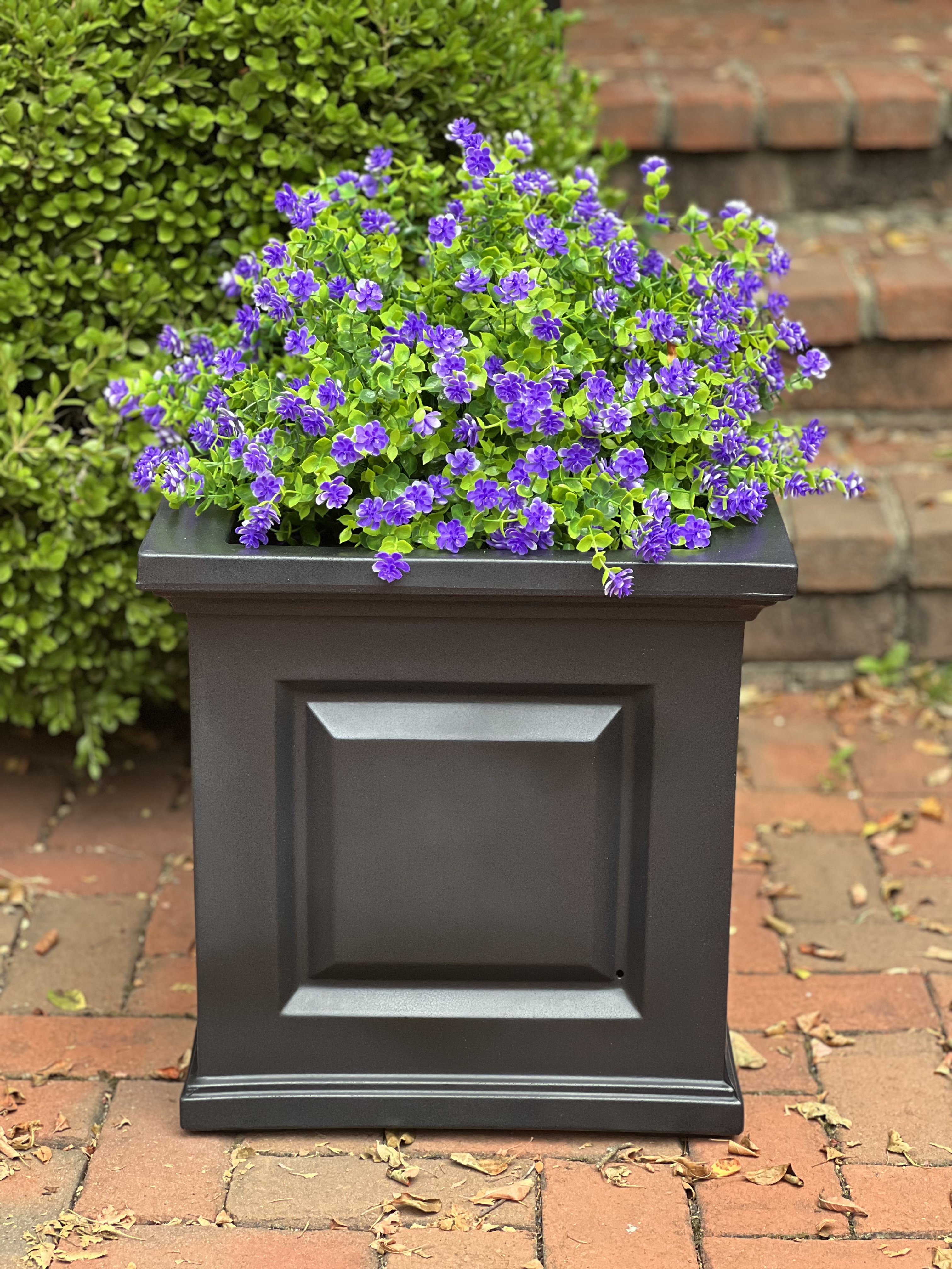 Image of faux plants (purple flowers) in a black metal planter.