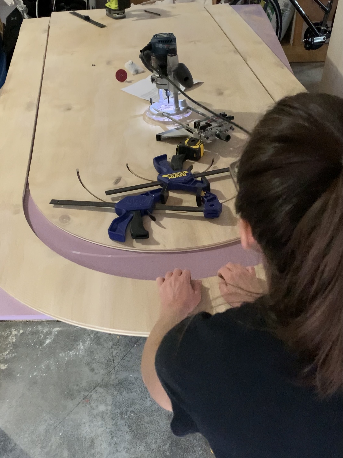 Hands pulling a wooden arch away from leftover plywood.